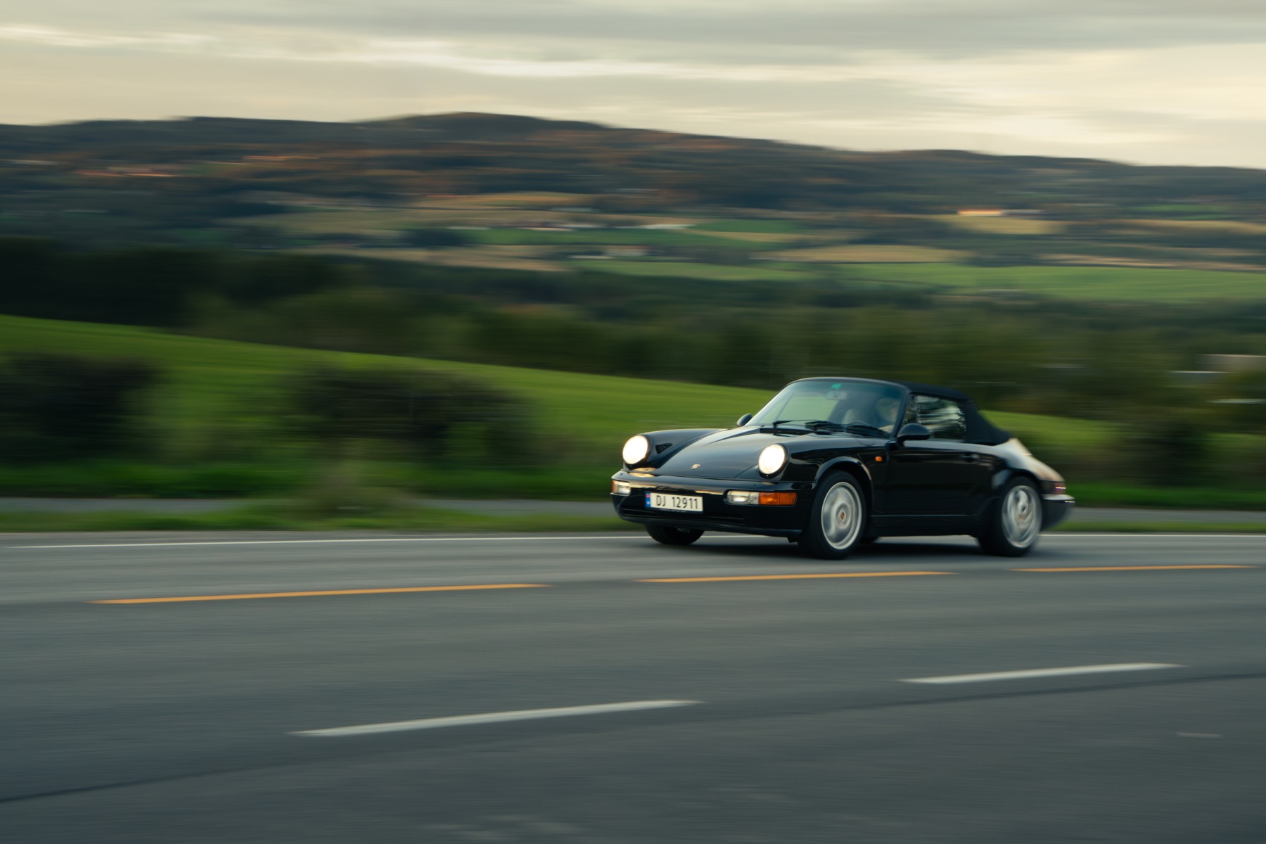 En svart Porsche i fart foran et landskap i bevegelse